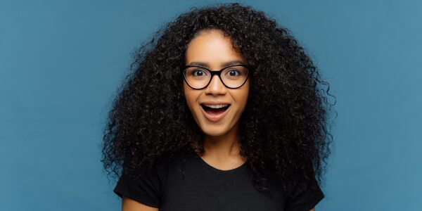 surprised young woman of color, wearing glasses